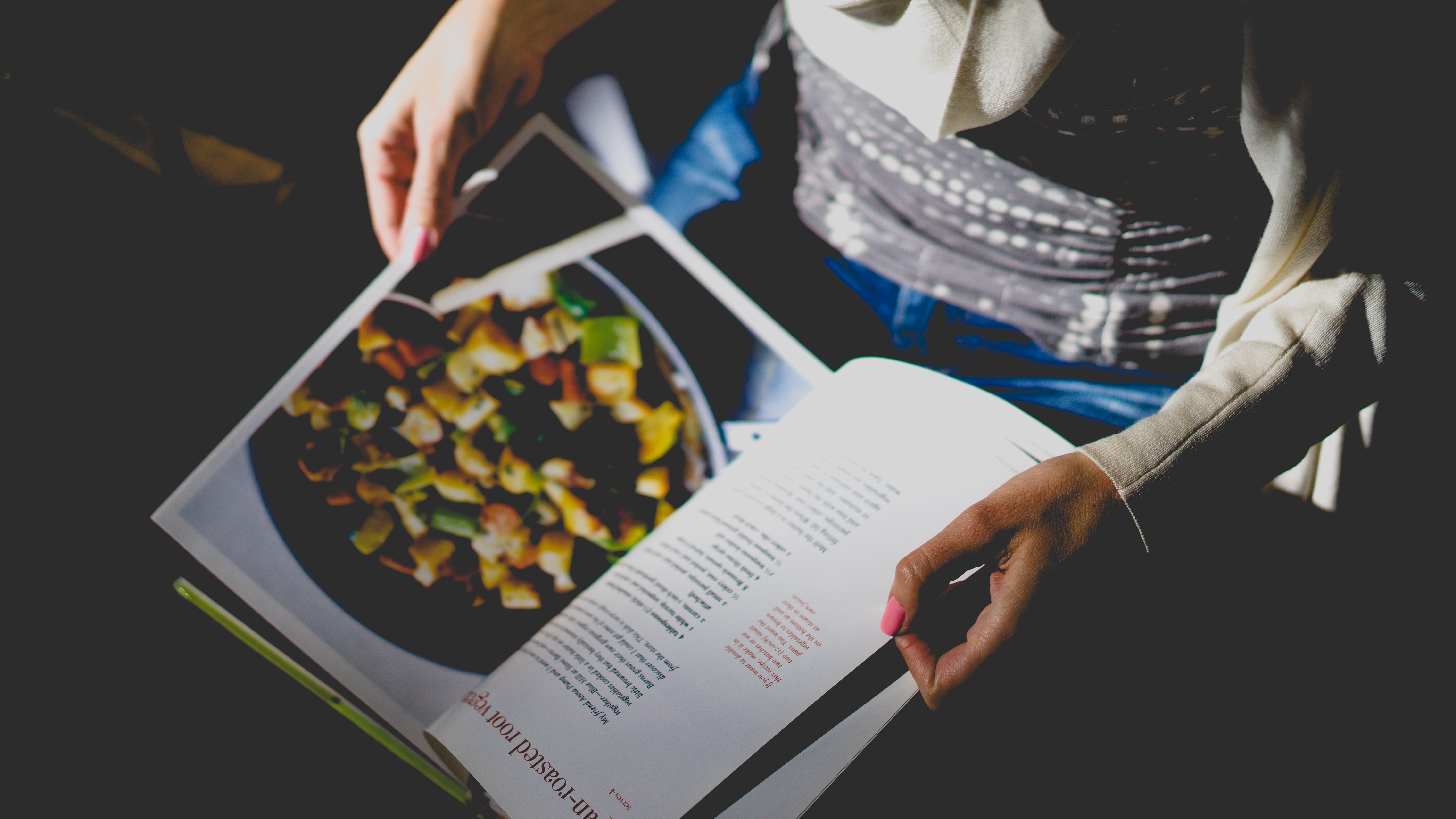 a woman flips through the pages of a cookbook by-dan-gold